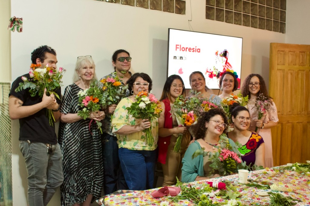 Grupo de participantes sonriendo con ramos de flores en un taller de Floresía Nanái